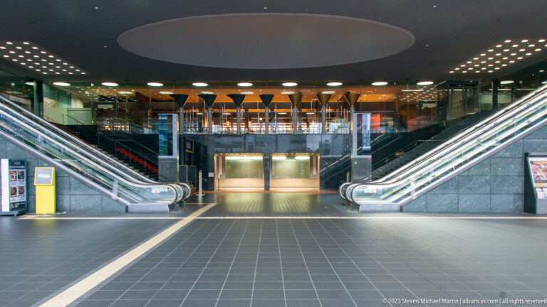 Symmetrical view of escalators beneath a circular ceiling feature.