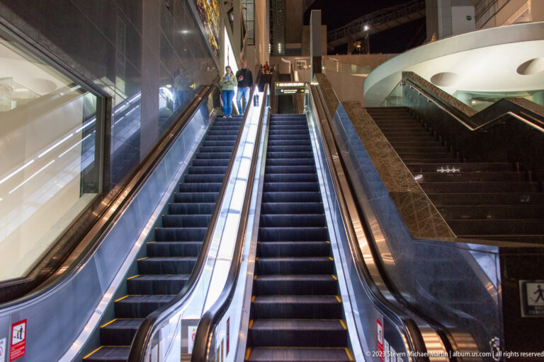 Two escalators beside a broad staircase rise through Kyoto Station's multi-level interior.
