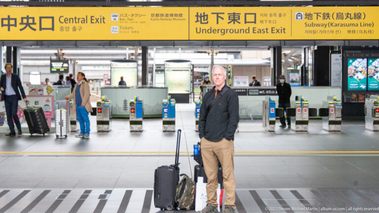 Traveler with luggage beneath station exit signs.