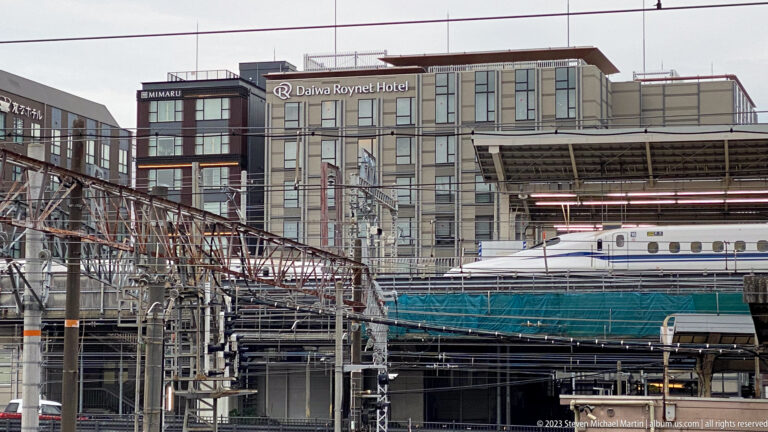Rail infrastructure with Shinkansen and surrounding buildings.