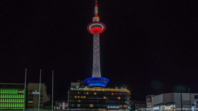 Centered night view of Kyoto Tower above the lit Kyoto Tower Building.