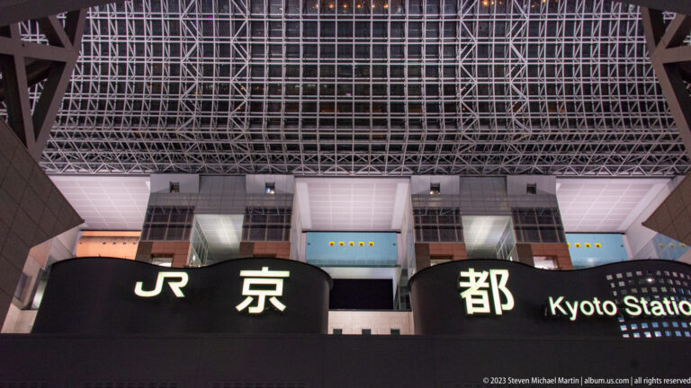 Illuminated Kyoto Station name on the exterior facade beneath the large steel-and-glass roof.