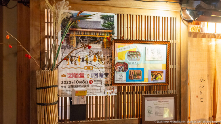 Restaurant entrance with event posters and menu display shown at night with the principal architectural, landscape, or street details visible in the composition.