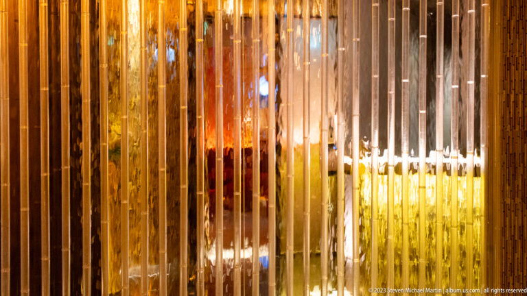 Vertical glass screen with warm interior lighting shown at night with the principal architectural, landscape, or street details visible in the composition.