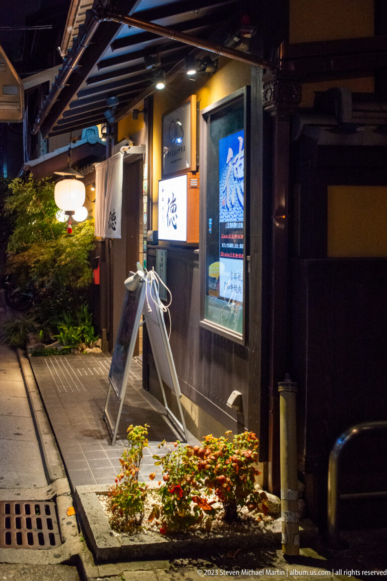 Traditional storefront with menu sign and illuminated lantern shown at night with the principal architectural, landscape, or street details visible in the composition.