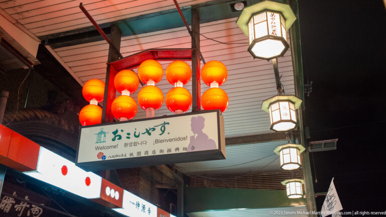 Red lanterns and multilingual welcome sign shown at night with the principal architectural, landscape, or street details visible in the composition.