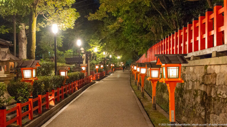 Lantern-lined path through Yasaka Shrine grounds shown at night with the principal architectural, landscape, or street details visible in the composition.