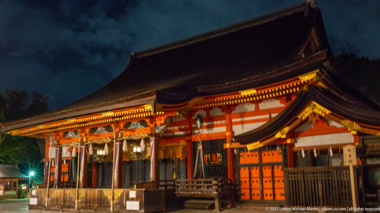 Oblique view of Yasaka Shrine main hall shown at night with the principal architectural, landscape, or street details visible in the composition.