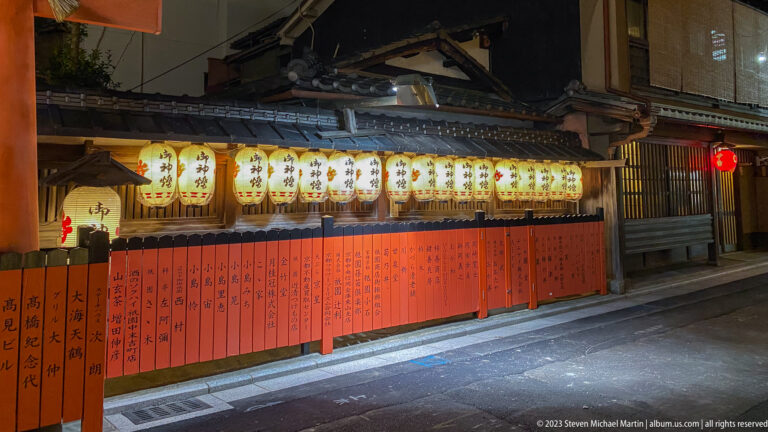 Rows of lanterns above vermilion fence shown at night with the principal architectural, landscape, or street details visible in the composition.