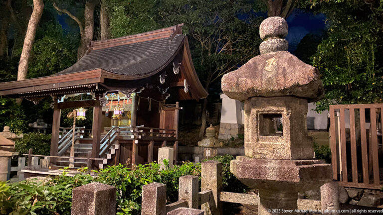 Small shrine with stone lantern shown at night with the principal architectural, landscape, or street details visible in the composition.