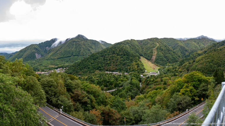 Wide mountain valley with forest, roads, buildings, and a cleared ski run.