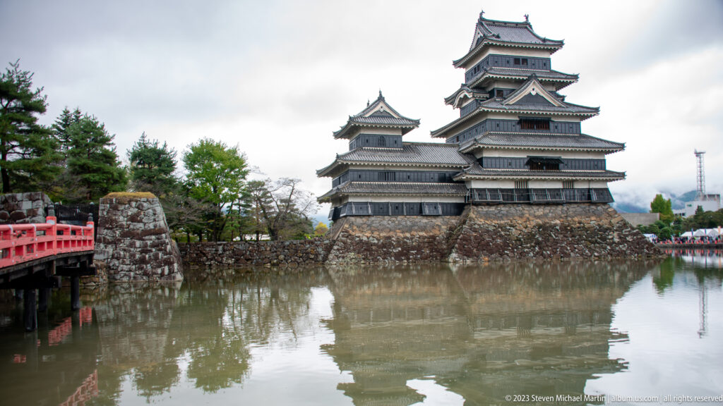 Matsumoto Castle across the moat with a red bridge entering from the left.