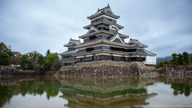Oblique view of Matsumoto Castle’s tiered keep above an angled stone base and moat.