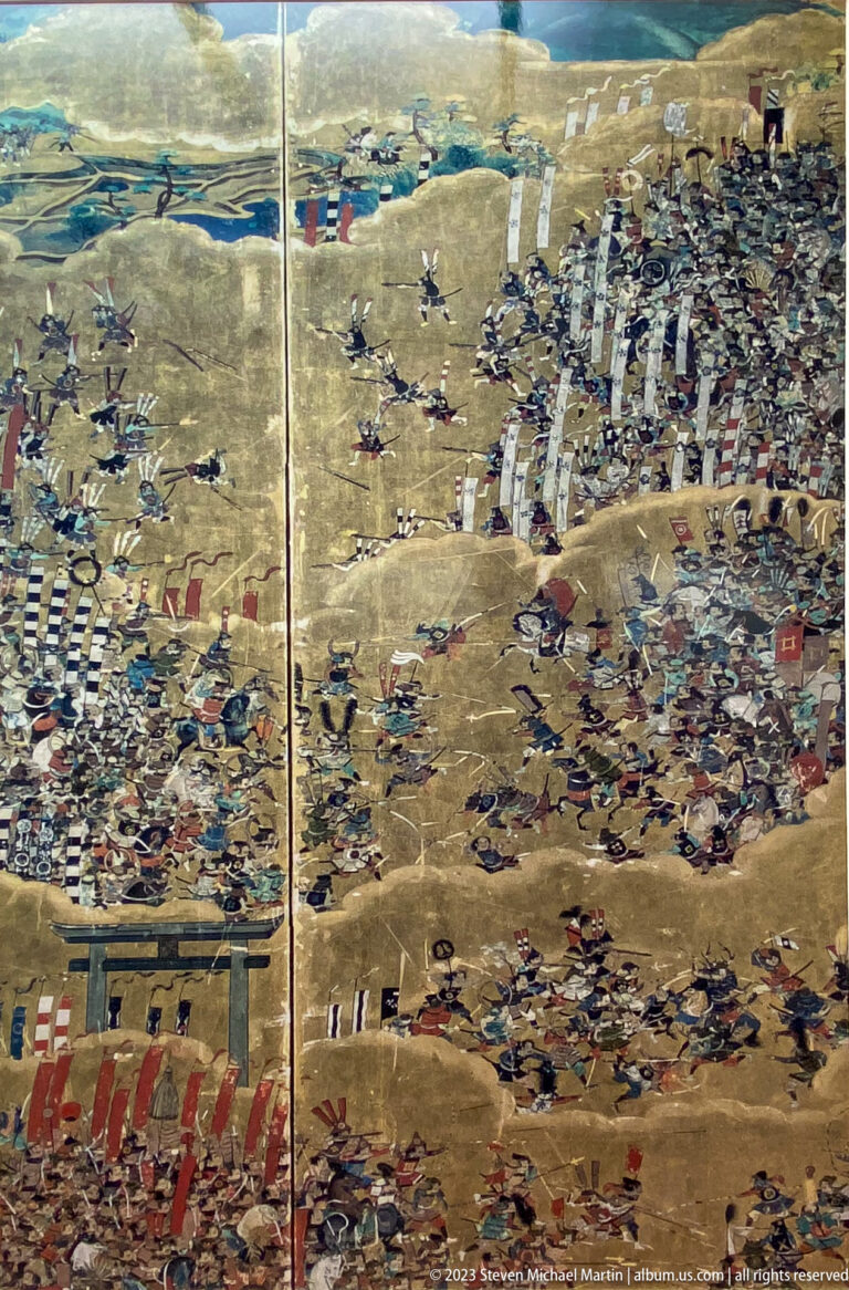Gold-ground Japanese folding screen crowded with mounted warriors, infantry, banners, and military encampments.