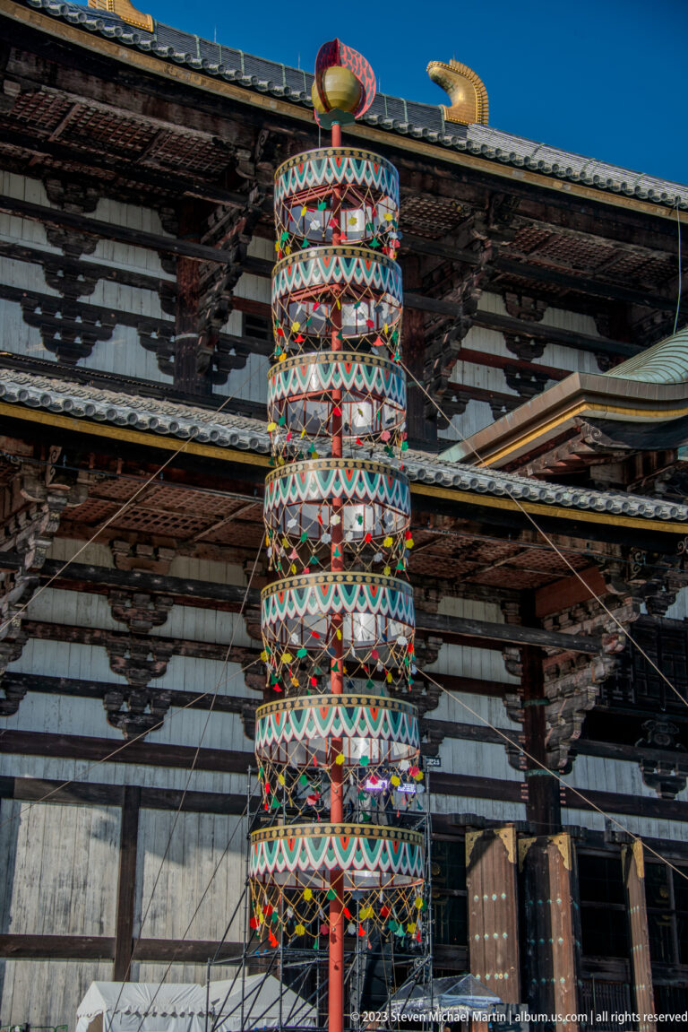 Close view of a brightly patterned cylindrical ceremonial tower against the Daibutsuden façade.