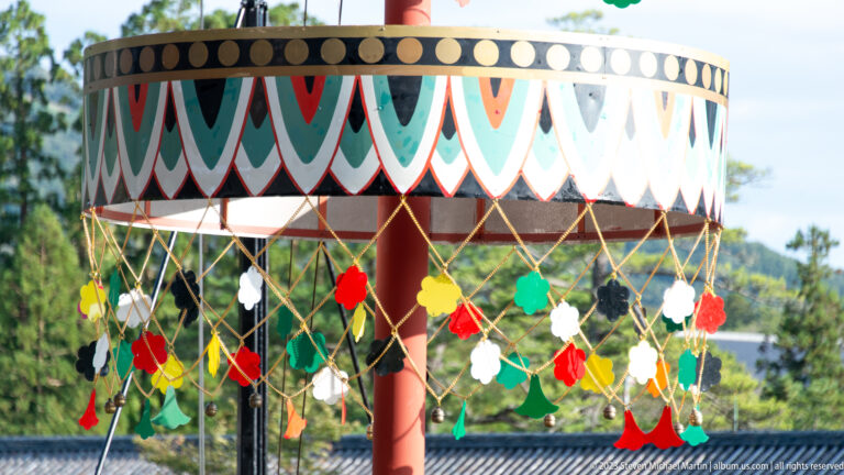 Painted circular canopy with black, white, red, and green bands and hanging colored ornaments.