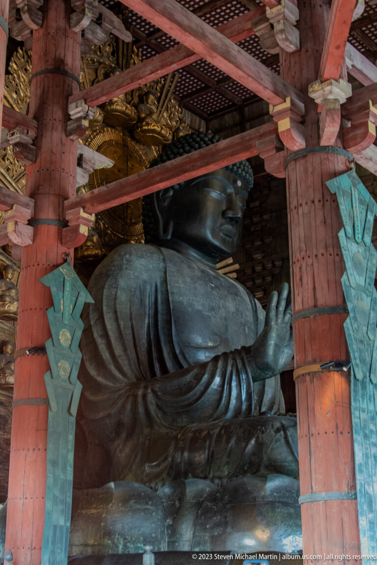 Side view of Todai-ji’s colossal bronze Vairocana Buddha between massive red timber columns.