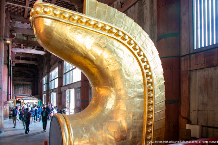 Large curved gilded halo element with rounded bosses inside the Great Buddha Hall.