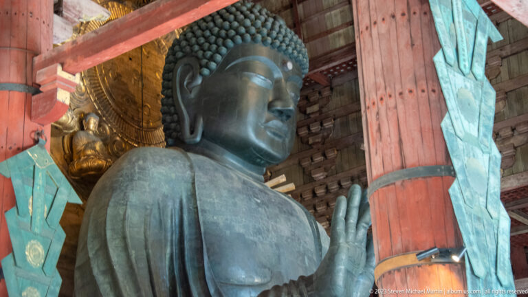 Close oblique view of Todai-ji’s bronze Vairocana Buddha with raised hand and gilded halo figures.