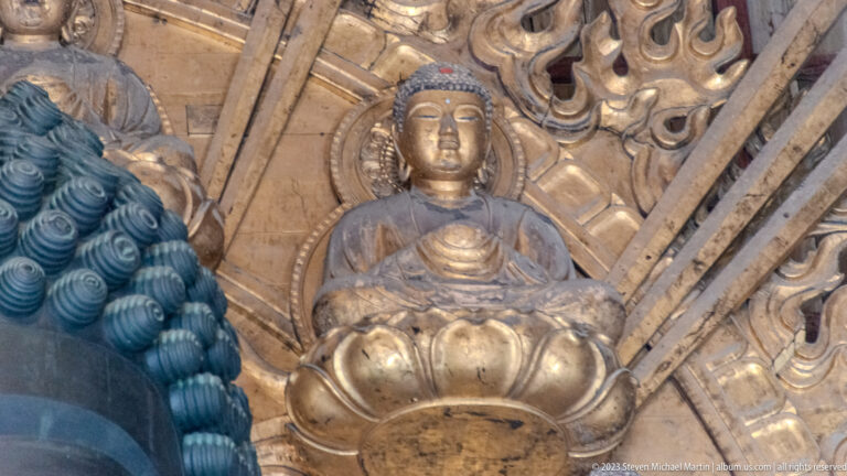 Small seated gilded Buddha on a lotus throne within the Daibutsu’s ornate halo.