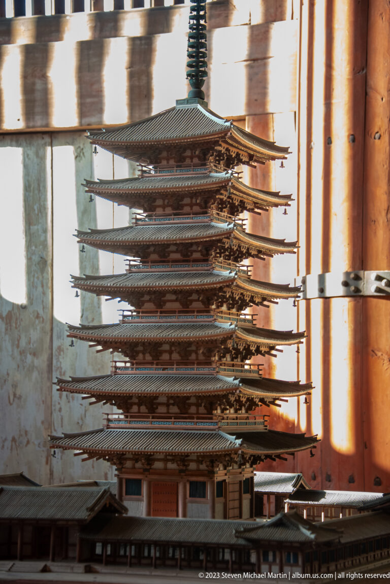 Row of slender multi-tiered wooden pagoda models displayed inside the temple hall.