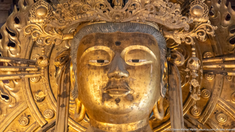 Close view of a gilded bodhisattva face framed by an ornate crown and halo.