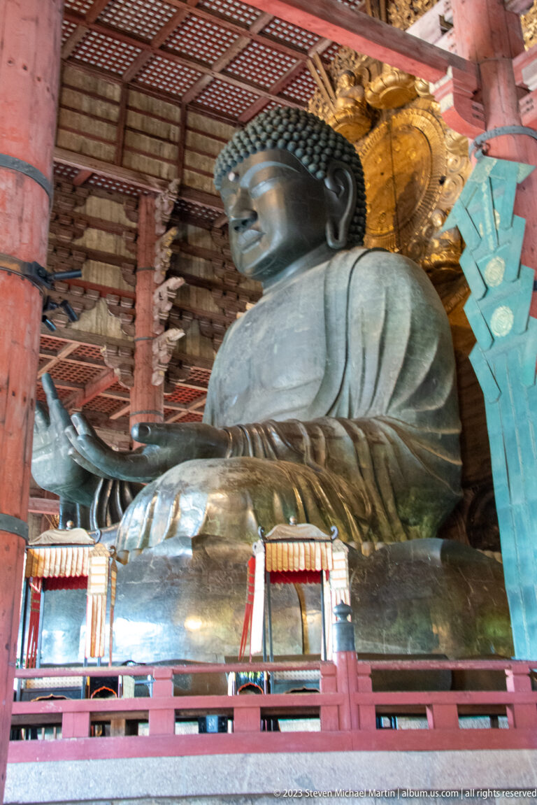 Side view of Todai-ji’s colossal bronze Daibutsu with raised hand and gilded halo.