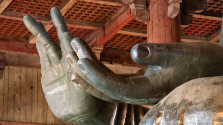 Close side view of the Great Buddha’s large bronze hand, fingers, and open palm.