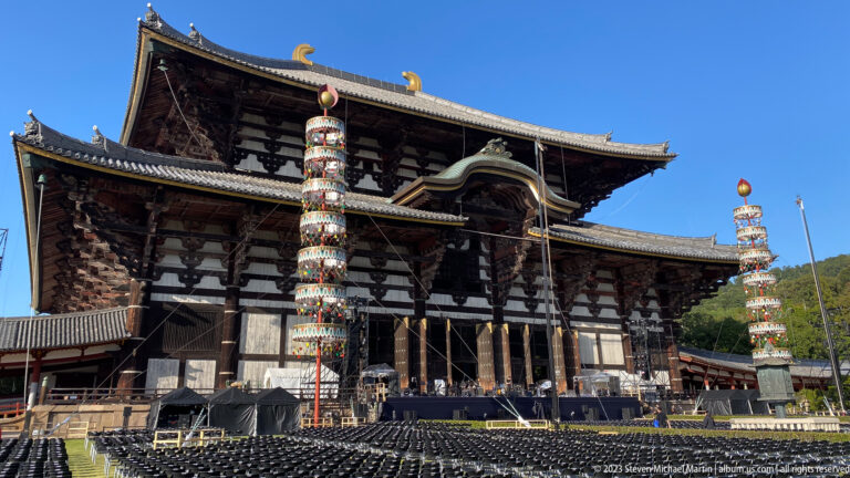 Todai-ji’s Great Buddha Hall with two colorful ceremonial towers standing before its dark timber façade.