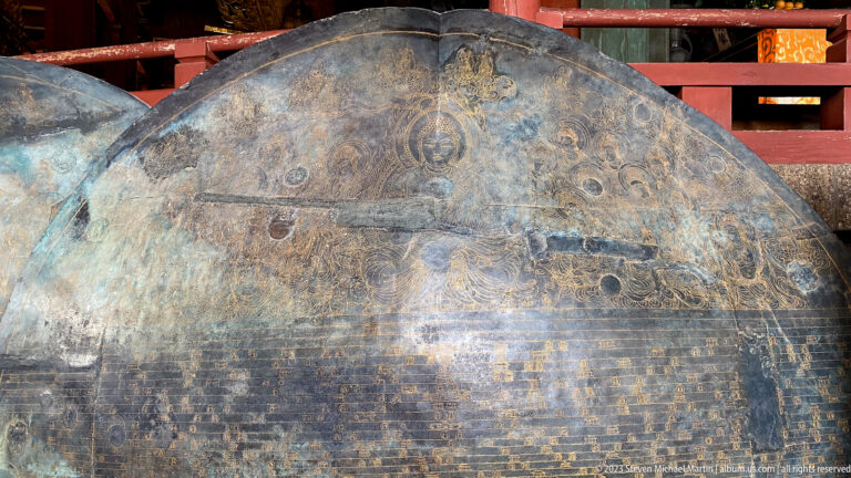Large arched bronze panel with dense inscriptions, engraved imagery, and a heavily weathered patina.