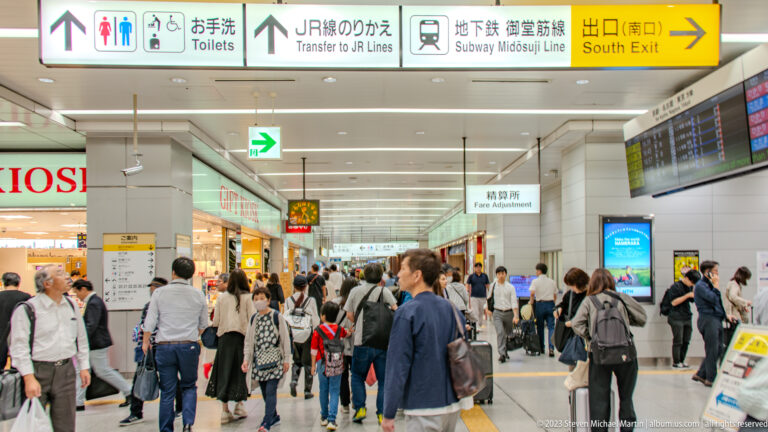 Crowded Osaka station concourse beneath JR transfer, Midosuji Line, and South Exit signs.