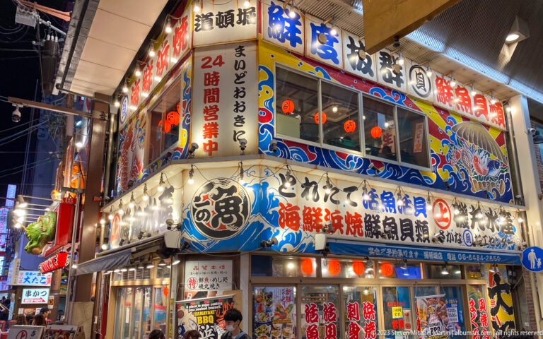 Bright two-storey seafood restaurant with wave graphics, fish signs, and diners upstairs.