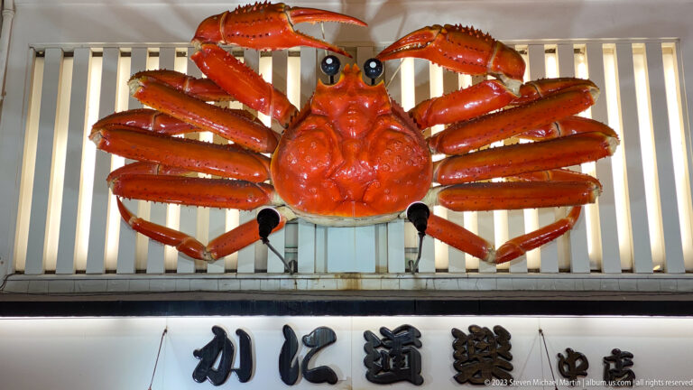 Giant red Kani Doraku crab sign mounted above a restaurant entrance.