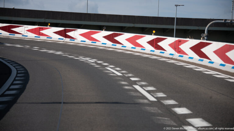 Curving Osaka roadway with dashed lane markings and red-and-white chevron barriers.