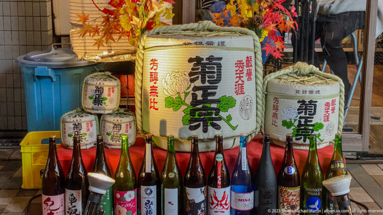 Decorative sake barrels and assorted bottles displayed outside an Osaka restaurant.
