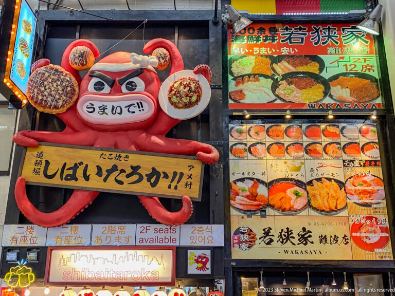 Red octopus mascot holding food signs above restaurant advertisements in Osaka.