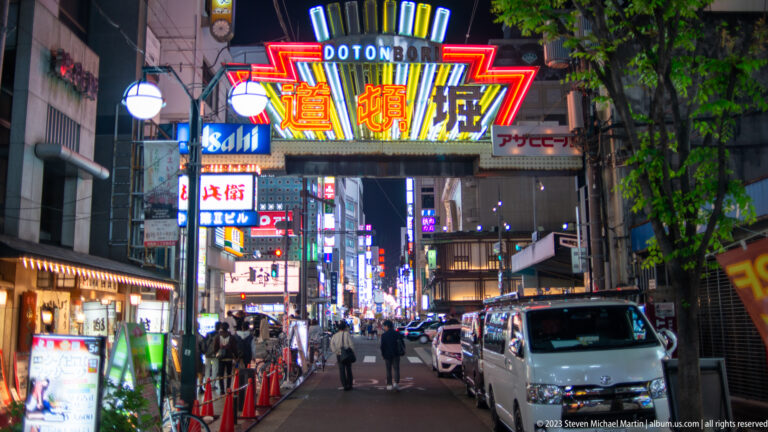 Illuminated Dotonbori gateway above a narrow Osaka nightlife street.