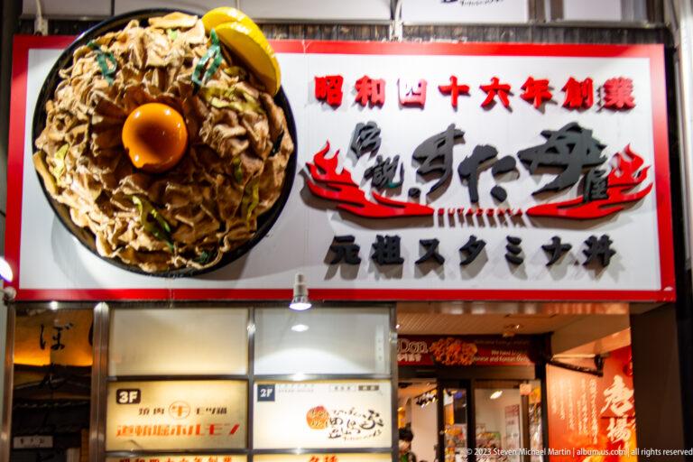 Large Osaka restaurant sign with a sculpted meat bowl topped by a raw egg.