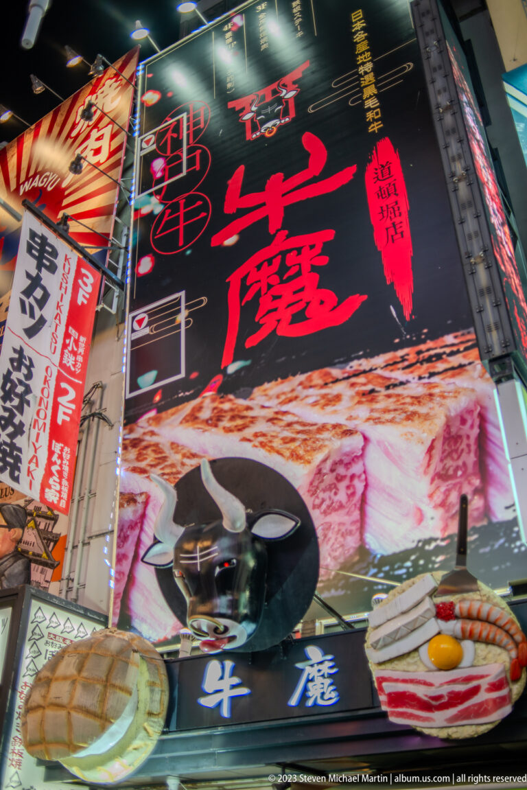 Large illuminated beef and steak billboard above an Osaka street.