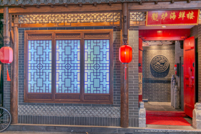 Chinese-style restaurant entrance with lattice windows, red lanterns, and dark wood.