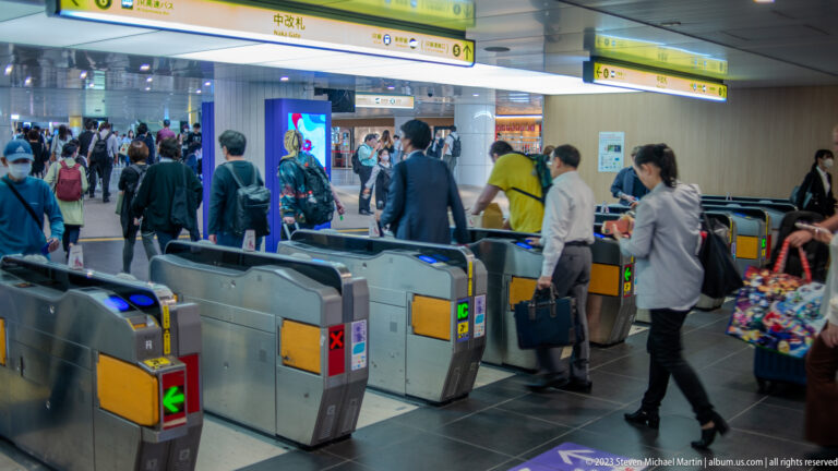 Passengers using Osaka Metro fare gates beneath yellow Chuo Line directional signs.