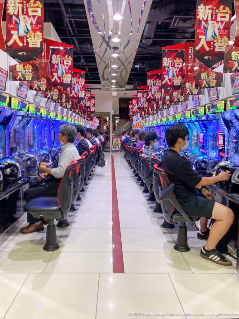 Central aisle between long rows of pachinko machines and seated players.