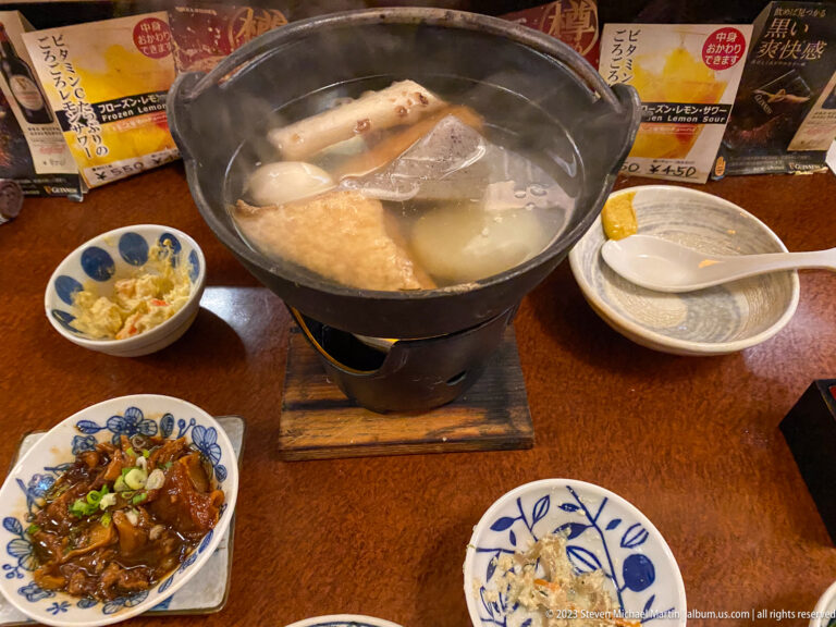 Steaming Japanese hot pot with daikon and fish cakes on a tabletop burner.