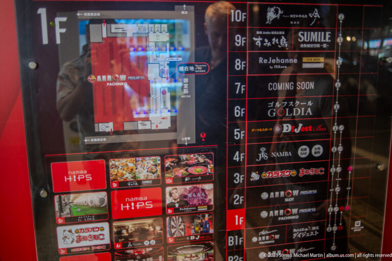 Reflective illuminated directory listing restaurants and entertainment venues by floor in Osaka.