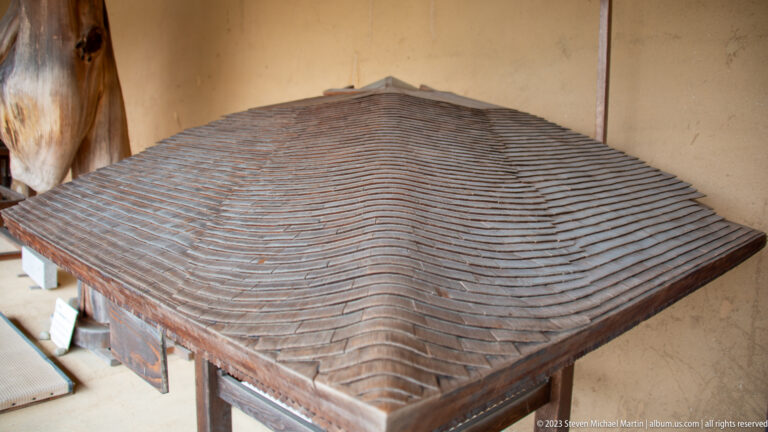Close view of hipped roof covered in many overlapping hand-split wooden shingles with varied grain and edges.