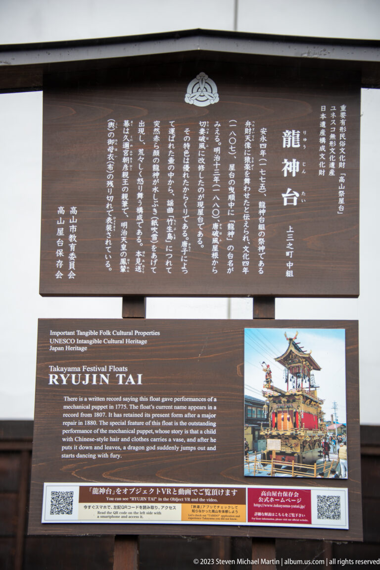 Bilingual Ryujin-tai information panel with Japanese and English text, a festival-float photograph, and QR codes.