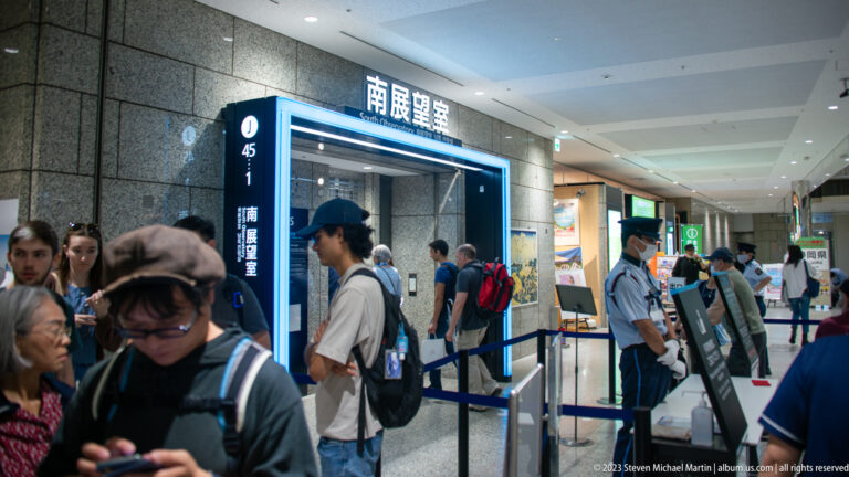 Visitors queue beside a blue-lit entrance sign for the south observation room inside the government building.