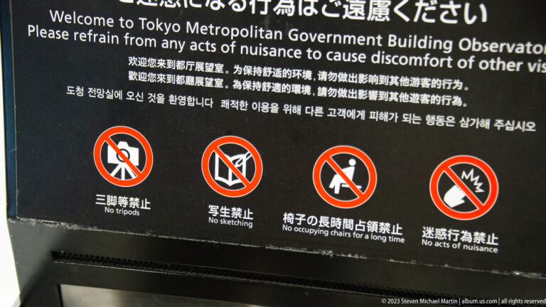 Multilingual observation-deck rules sign with red symbols banning tripods, sketching, chair occupation, and nuisance behavior.