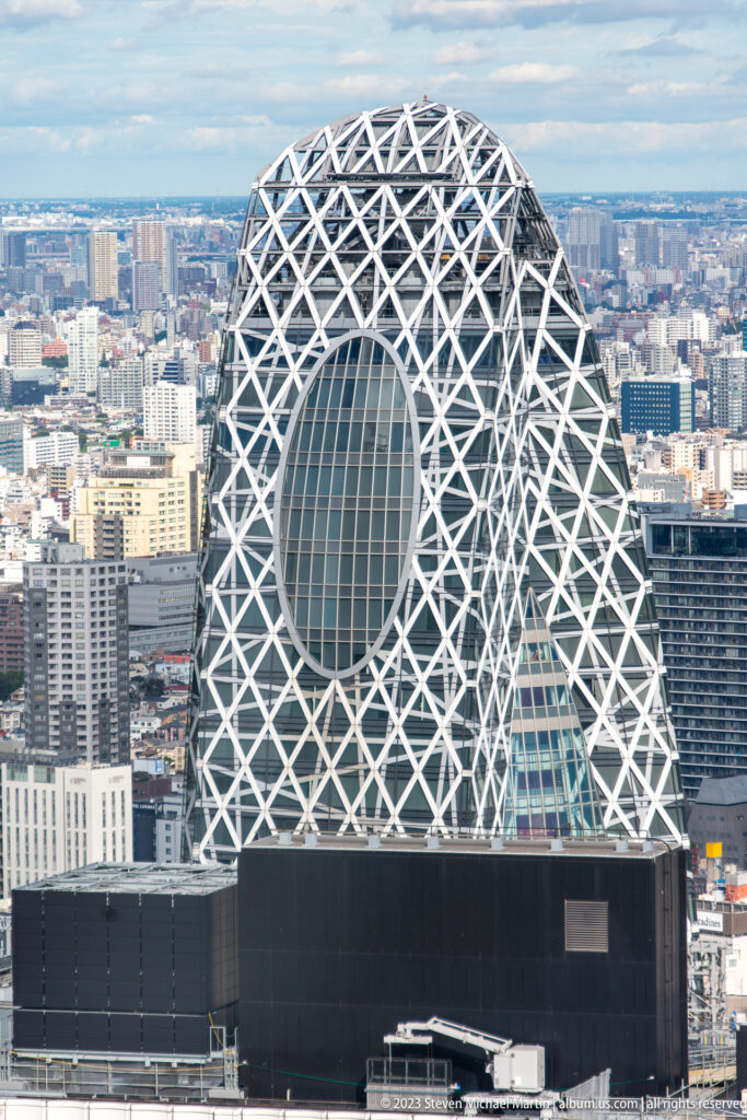 Elevated close view of the Mode Gakuen Cocoon Tower’s white lattice, oval opening, and curved glass façade.