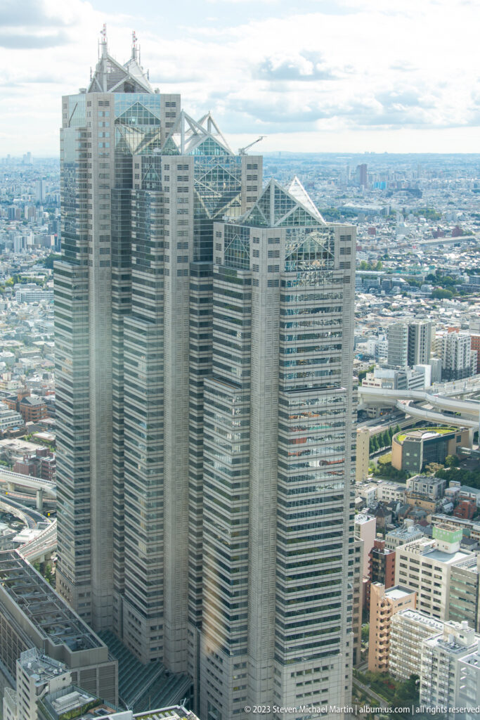 Elevated view of Shinjuku Park Tower with three stepped volumes and triangular roof structures.